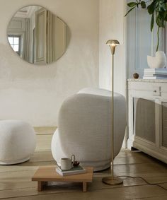 a living room with a round mirror on the wall and two bean chairs in front of it