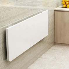 a white radiator mounted to the side of a wall next to fruit on a counter