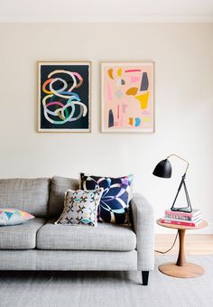 a living room with two paintings on the wall and a couch in front of it