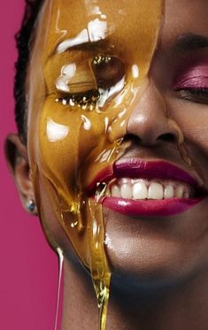 a woman with her face painted gold and dripping liquid from the top of her mouth