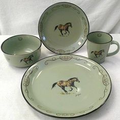 four cups and two saucers with horses painted on the sides are sitting on a white tablecloth