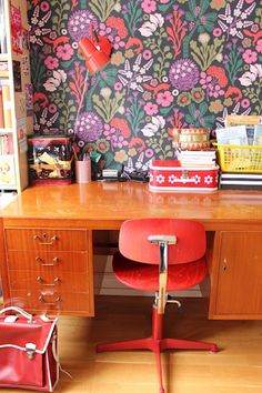 a red chair sitting in front of a wooden desk