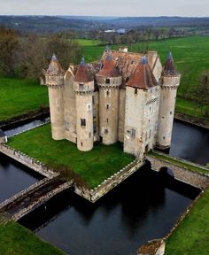 an aerial view of a castle with water in the foreground and green fields behind it