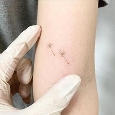 a person is getting a tattoo on their arm with a dandelion in the middle