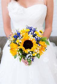 a bride holding a bouquet of sunflowers and baby's breath