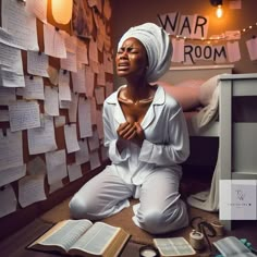 a woman sitting on the floor in front of a wall covered with notes and books