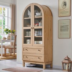 a wooden cabinet with glass doors and drawers in a living room next to a window