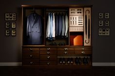 an organized closet with suit and tie hanging on the wall next to it is shown