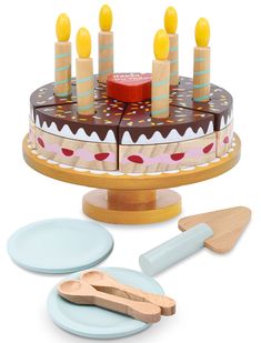 a cake with candles on it and two plates next to it, including a spatula