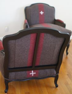 a chair with a cross painted on the back and red stripeing around it, sitting on a hard wood floor