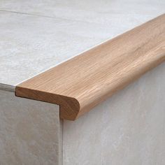 a close up view of a wooden edge on a white wall with tile flooring