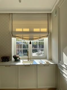 a kitchen with white cabinets and an open window