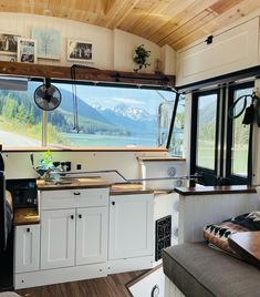 a kitchen area with an oven, sink and window overlooking the mountains in the background