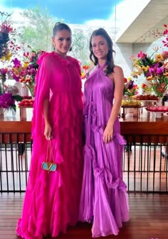 two women standing next to each other in dresses