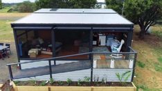 a small house sitting on top of a wooden deck next to a yard with tables and chairs