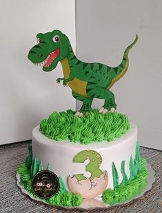 a dinosaur cake with green frosting and decorations on it's top, sitting on a table