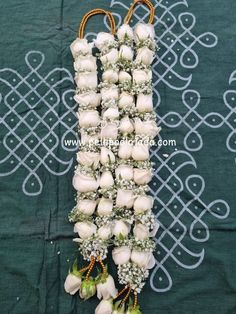 white roses arranged in the shape of a letter on a green cloth with beads and flowers