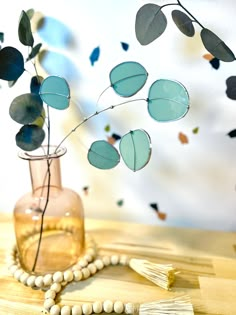 a vase filled with flowers on top of a wooden table next to a beaded necklace