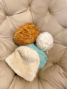 two crocheted balls of yarn sitting on top of a white chair cushiones