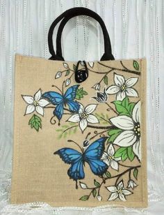 a handbag with blue butterflies and white flowers on the front is sitting on a lace tablecloth