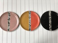 three plates with different designs on them sitting next to each other in front of a striped wall