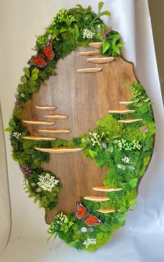 a wooden board that has plants and butterflies on it with grass growing all around the edges