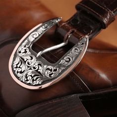 a brown leather chair with a metal buckle on the seat and an ornate pattern around it