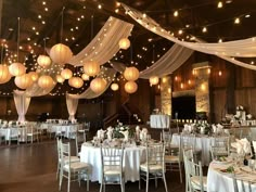 a banquet hall decorated with white linens and paper lanterns