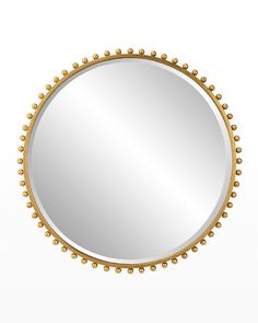 a round mirror with beading around the edges and an oval frame, on a white background