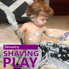 a young child sitting on the floor with paint all over his body and hands, playing with toys