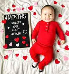 a baby laying on top of a bed next to a sign that says 4 months consider your heart stolen