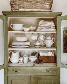 an old china cabinet with dishes and cups