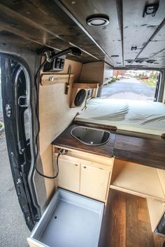 the interior of a camper with its bed and sink in place to be used as a kitchen