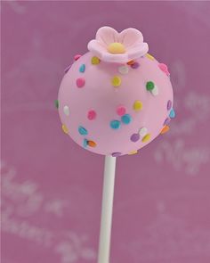 a pink cake pops with sprinkles and a flower on top