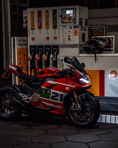 a red motorcycle parked in front of a gas station