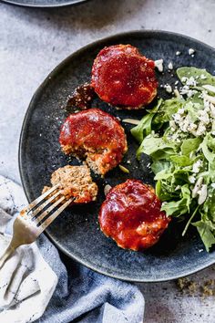 two meat patties with ketchup and lettuce on a black plate