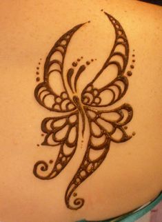 the back of a woman's shoulder with henna tattoos on it and an intricate butterfly