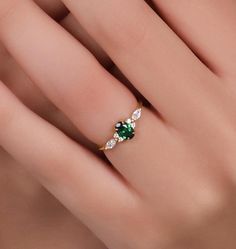 a woman's hand with an emerald and diamond ring