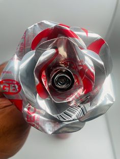 a silver and red flower shaped object sitting on top of a wooden table next to a white wall