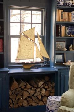 a sailboat is sitting on top of a book shelf in front of a window