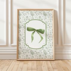 a frame with a green bow hanging from it's side on a wooden floor