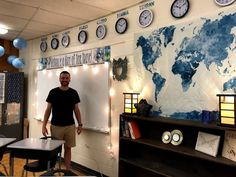 a man standing in front of a whiteboard with clocks on the wall above it