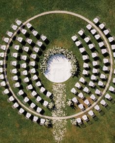 an aerial view of a wedding ceremony setup in the middle of a grassy area with white chairs