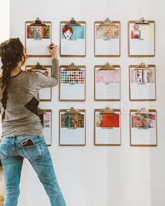 a woman standing in front of a wall with calendars hanging on it's sides