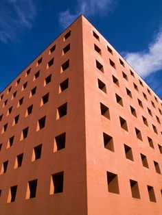 a tall brick building with holes in it's sides against a bright blue sky