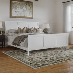 a white bed sitting in a bedroom on top of a hard wood floor next to a window