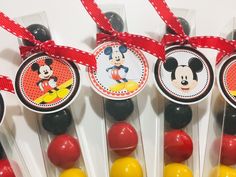 mickey mouse lollipops are on display with red ribbon around the top and yellow, orange, and black lollipops in front