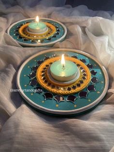 two tea lights sitting on top of a blue and yellow plate next to each other