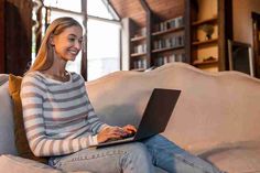 a woman sitting on a couch using a laptop computer