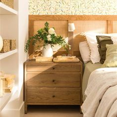 a bed room with a neatly made bed next to a night stand and shelf filled with books